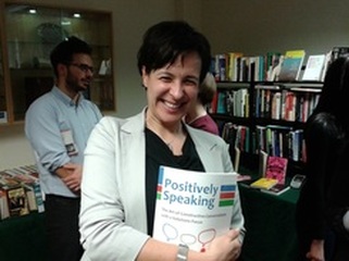 A buyer of Positively Speaking holding the book she has bought, smiling